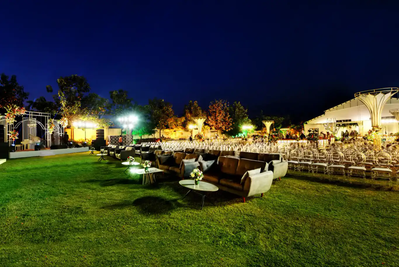 Lounge seating on the lit lawn at night at Sportico Resorts near Bangalore