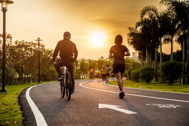 Team cycling and running on a park road at sunset